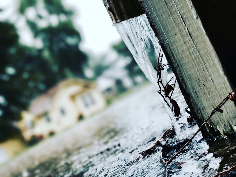 Rainwater flowing through properly functioning gutters during storm
